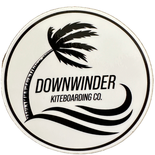 Round sticker of the Downwinder Kiteboarding Co. logo.The logo shows a palm tree blowing over with waves below it. Text says "Downwinder Kiteboarding Co."