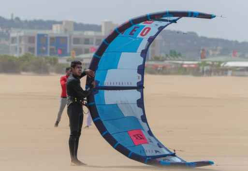 Kiteboarder holding a kite on its side for another person to launch.